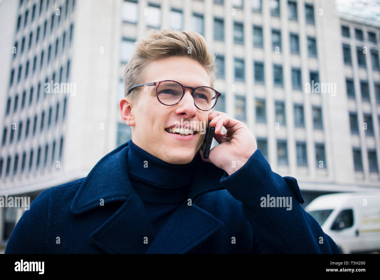 Ritratto di giovane sorridente uomo parlando al cellulare nella città Foto Stock