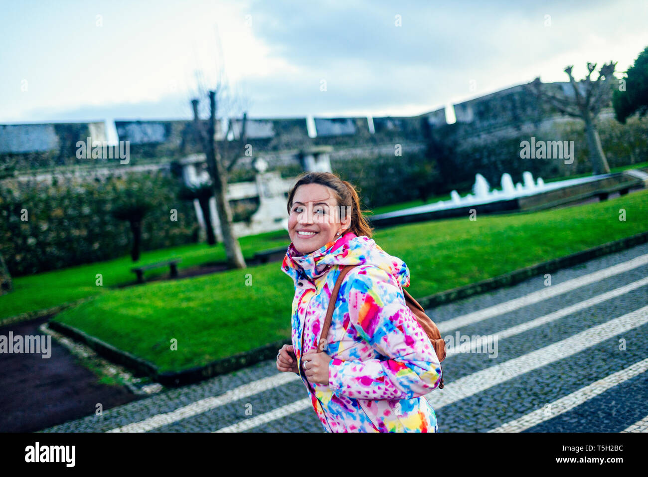 Il Portogallo, isole Azzorre, San Miguel, ritratto di donna sorridente a piedi attraverso Ponta Delgada Foto Stock