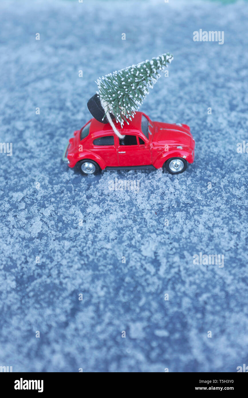 Red VW Beetle giocattolo auto con albero di Natale sul tetto in condizioni di neve Foto Stock