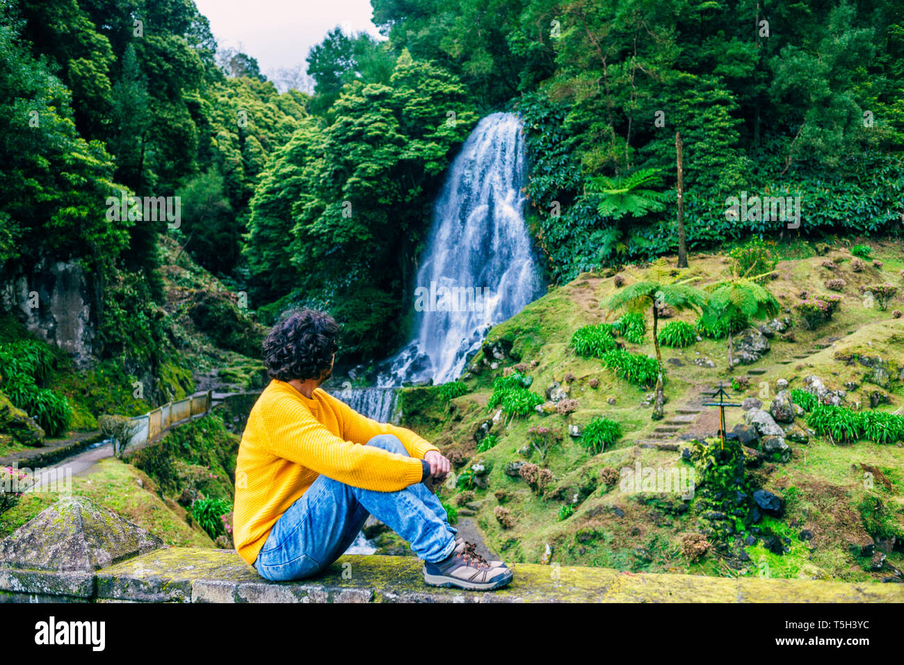 Il Portogallo, isole Azzorre, Sao Miguel, l'uomo seduto guardando una cascata Foto Stock