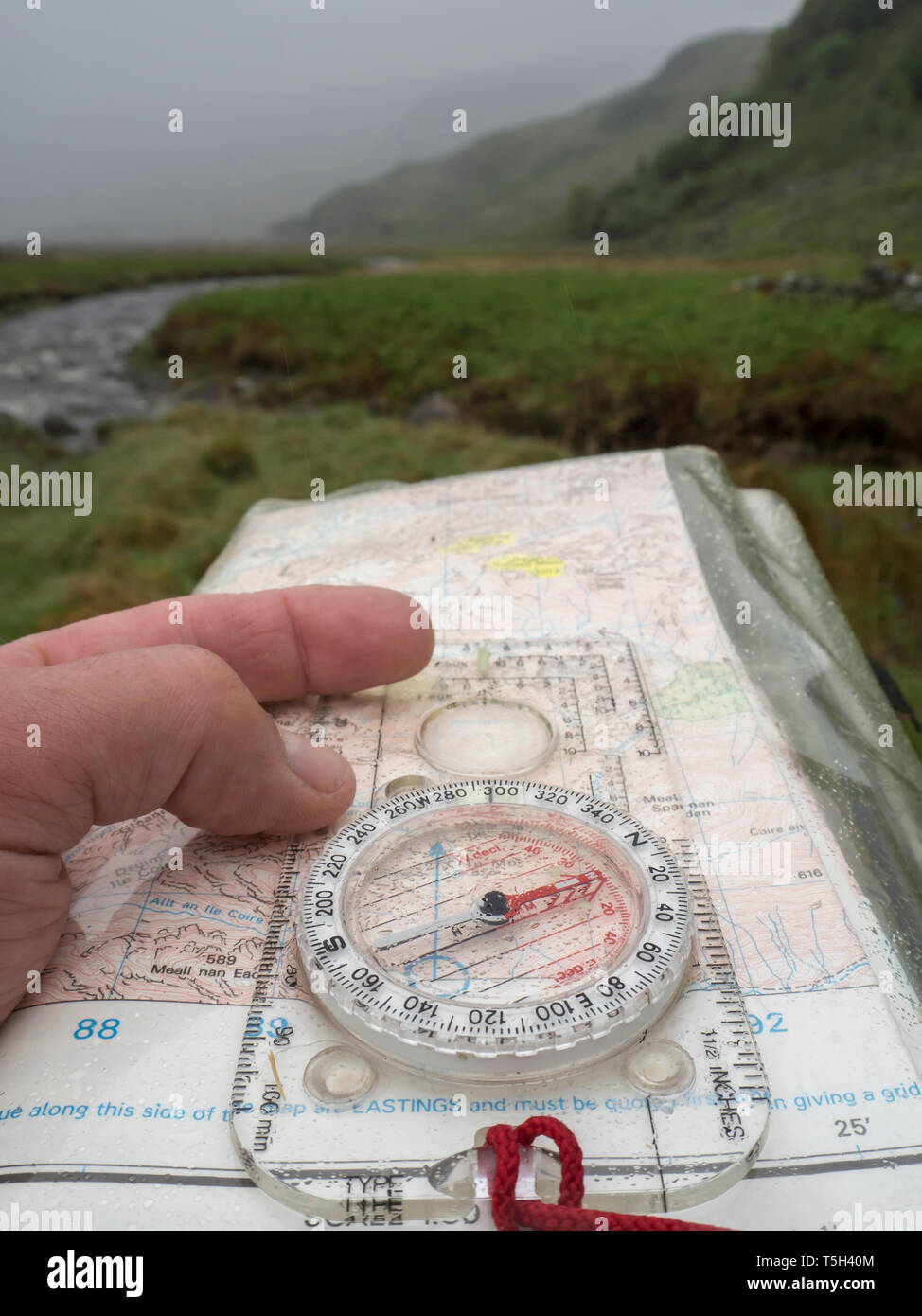 Gran Bretagna, Scozia, Knoydart penisola, la mano che tiene la bussola e la mappa durante la pioggia Foto Stock