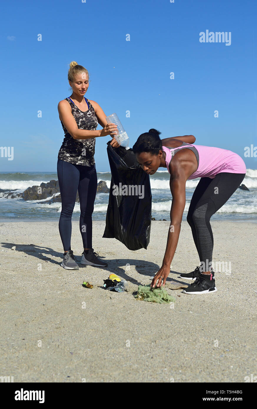 Due donne la pulizia della spiaggia dai rifiuti in plastica Foto Stock