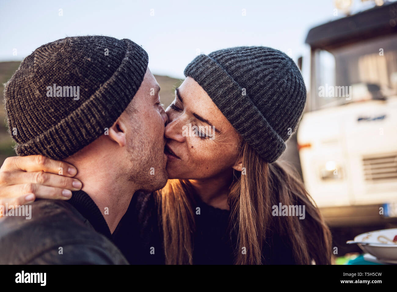 Kissing giovane indossando wooly cappelli Foto Stock