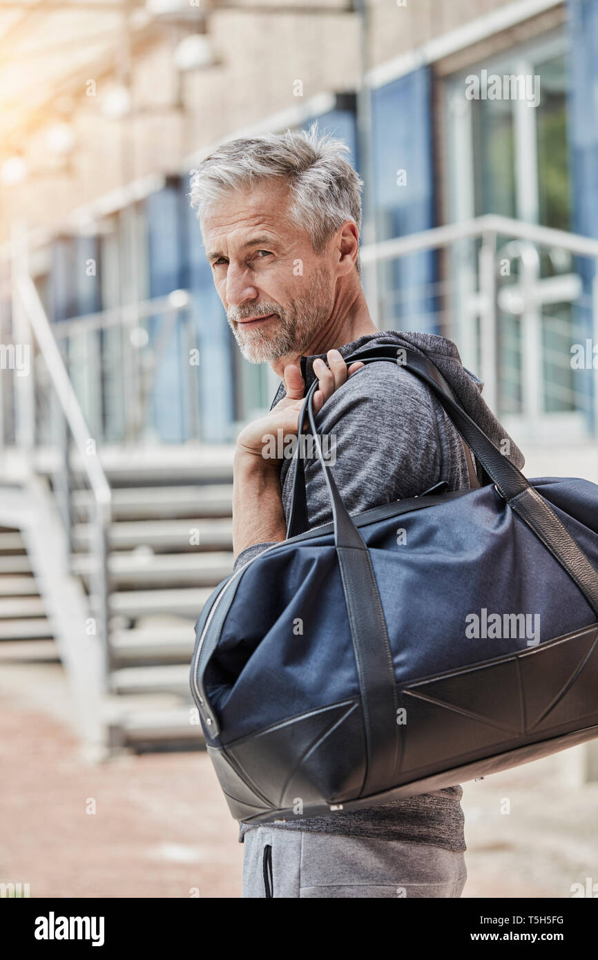 Ritratto di uomo maturo con borsa sportiva in piedi nella parte anteriore della palestra Foto Stock