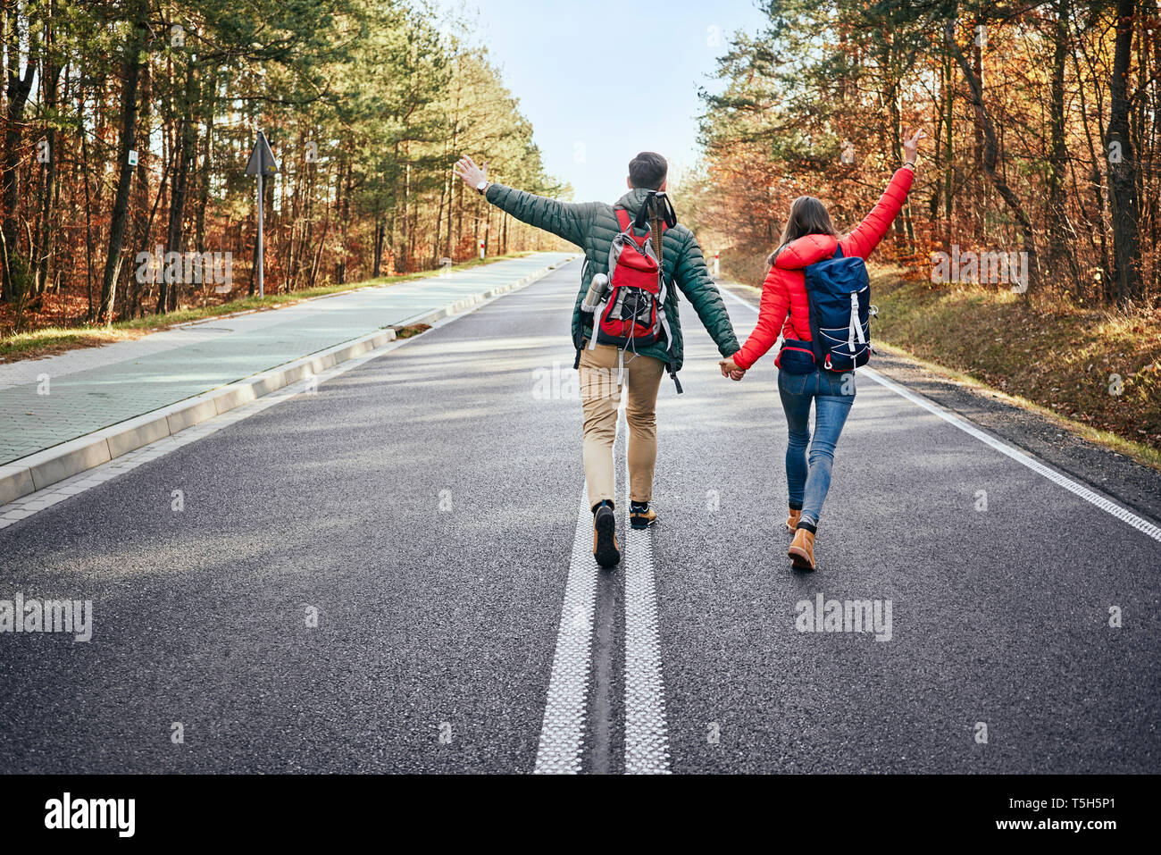 Coppia felice a piedi nel centro di una strada vuota nel bosco Foto Stock