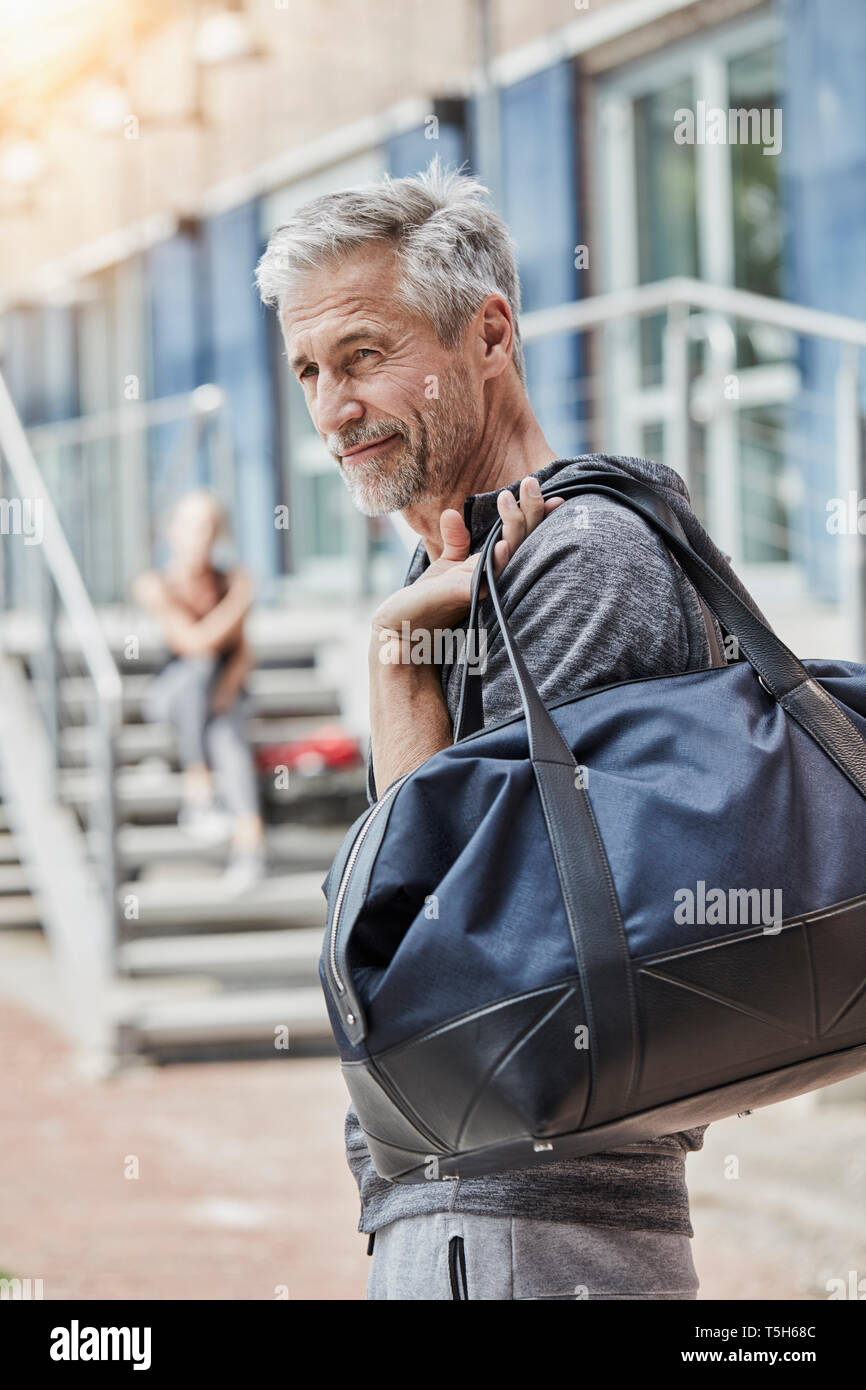 Ritratto di uomo maturo con borsa sportiva in piedi nella parte anteriore della palestra Foto Stock