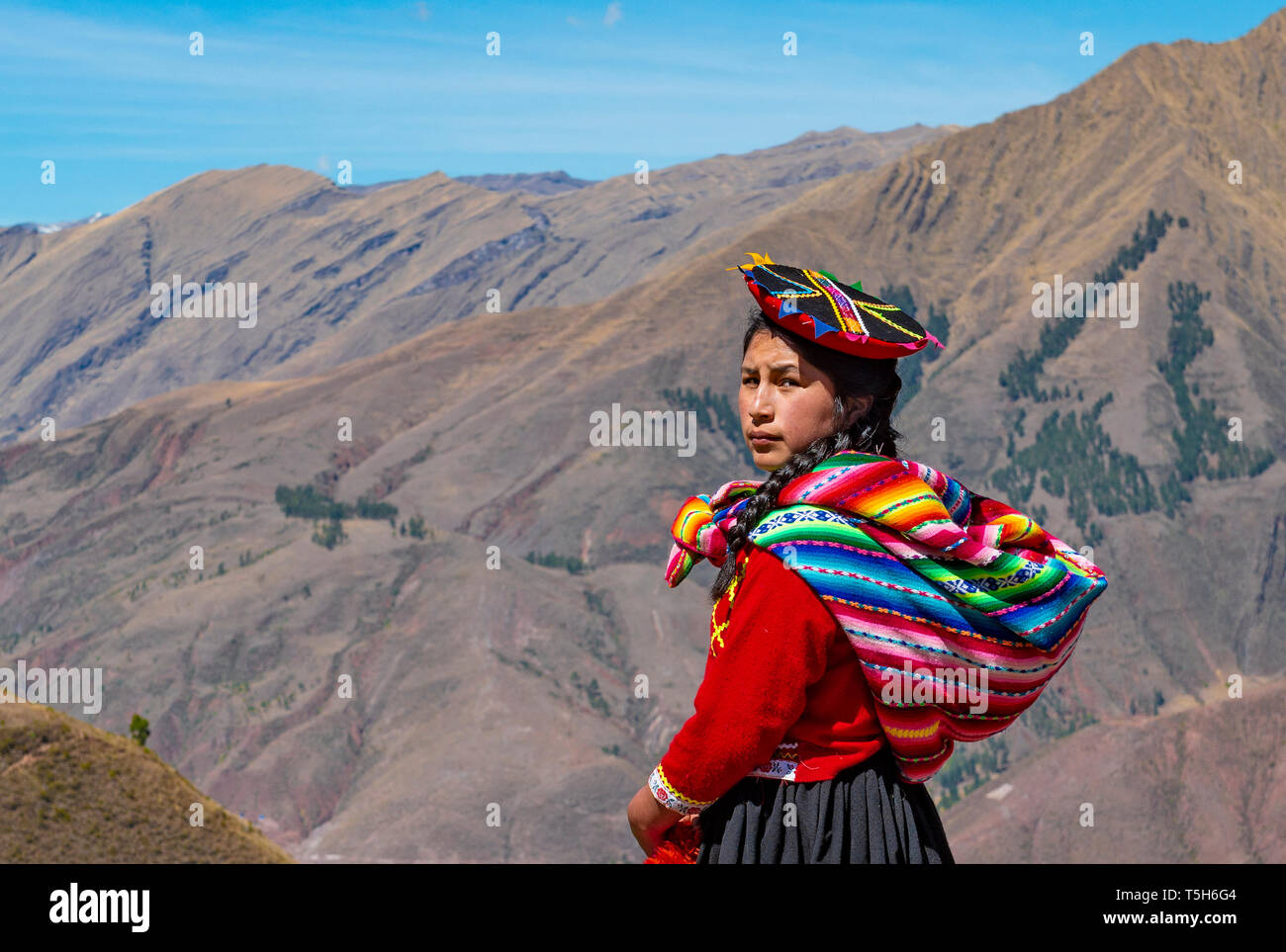 Ritratto di un indigeno Quechua ragazza guardando dietro di lei con la cordigliera delle Ande in background nei pressi di Cusco, Perù. Foto Stock