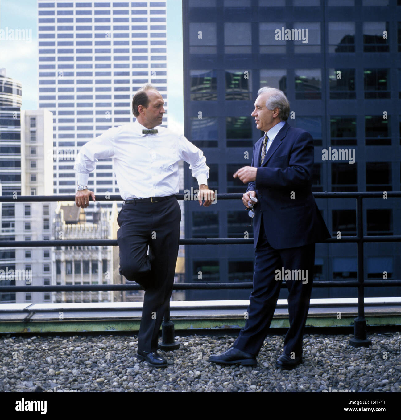 Due imprenditore maturo in piedi accanto ad una ringhiera su un balcone in città. Foto Stock