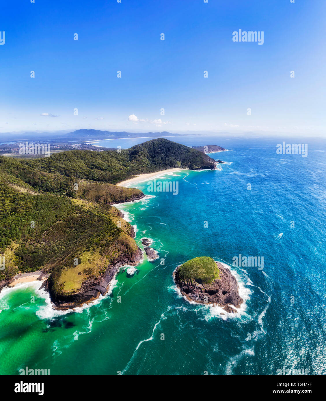 New Scenic 5 posti della costa Arakoon con appartate spiagge sabbiose e piccola vegetazione Rocks off shore nell'oceano Pacifico in verticale panorama dell'antenna. Foto Stock