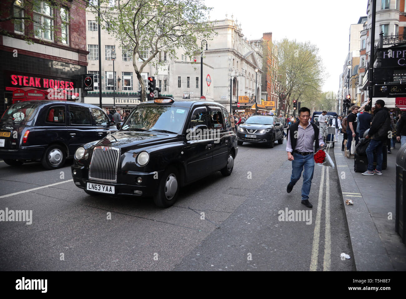 Taxi nero & man che trasportano fiori sulla carbonizzazione Cross Road, Londra. Inghilterra, Regno Unito Foto Stock