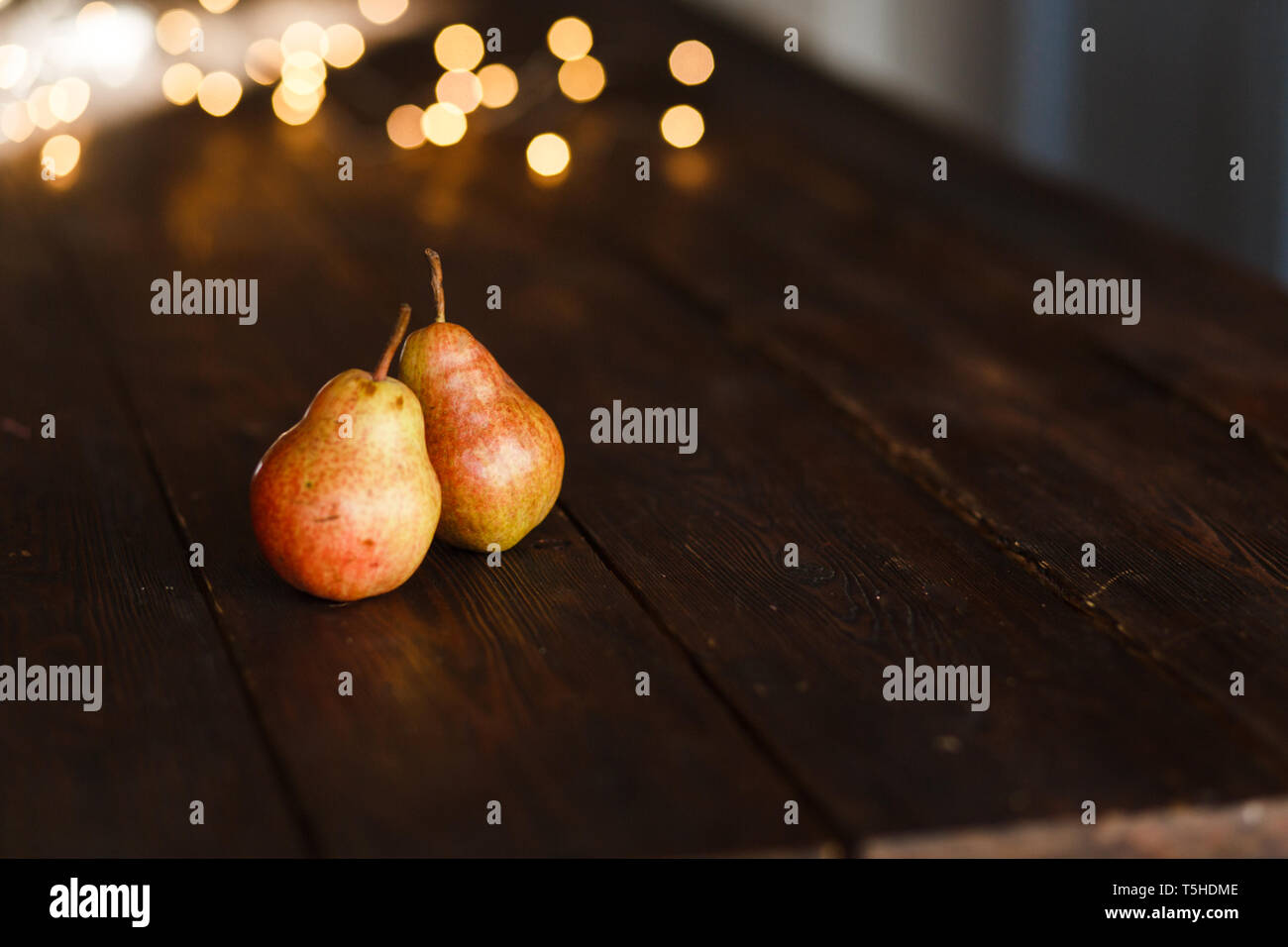 Bella mature Gustose pere su una cucina grande tavolo in legno con una ghirlanda di luci. Un bellissimo screen saver per un articolo che parla di alimenti sani, un c Foto Stock