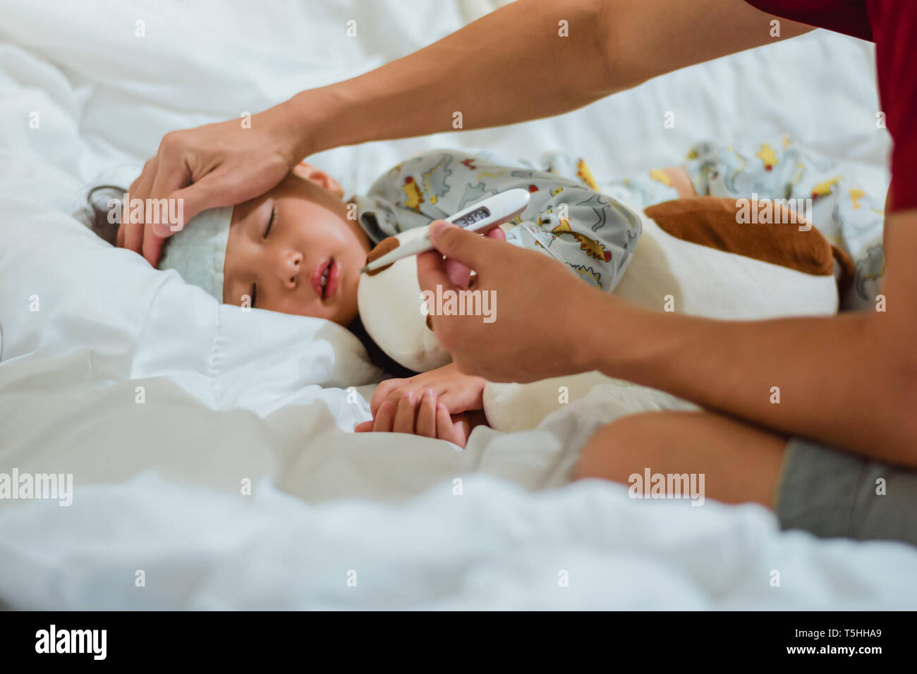 Padre tenendo il termometro in primo piano del malato bambina in camera da letto a notte tempo per monitorare la febbre alta con termometro per ,Kid ha avuto la febbre alta e Foto Stock