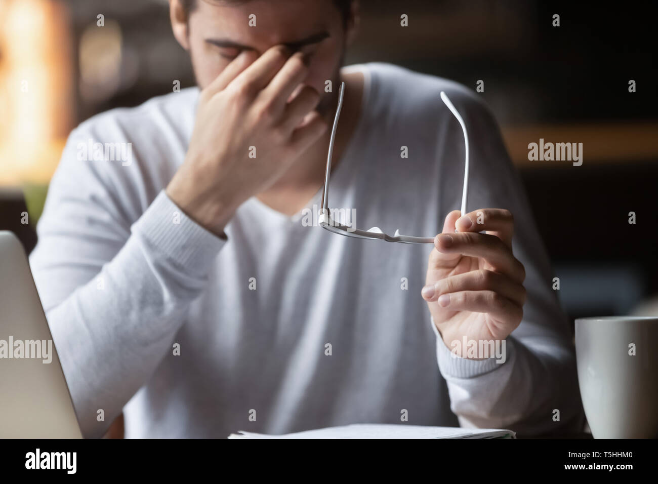 Stanco di computer imprenditore tenendo fuori i bicchieri si sente affaticamento degli occhi Foto Stock