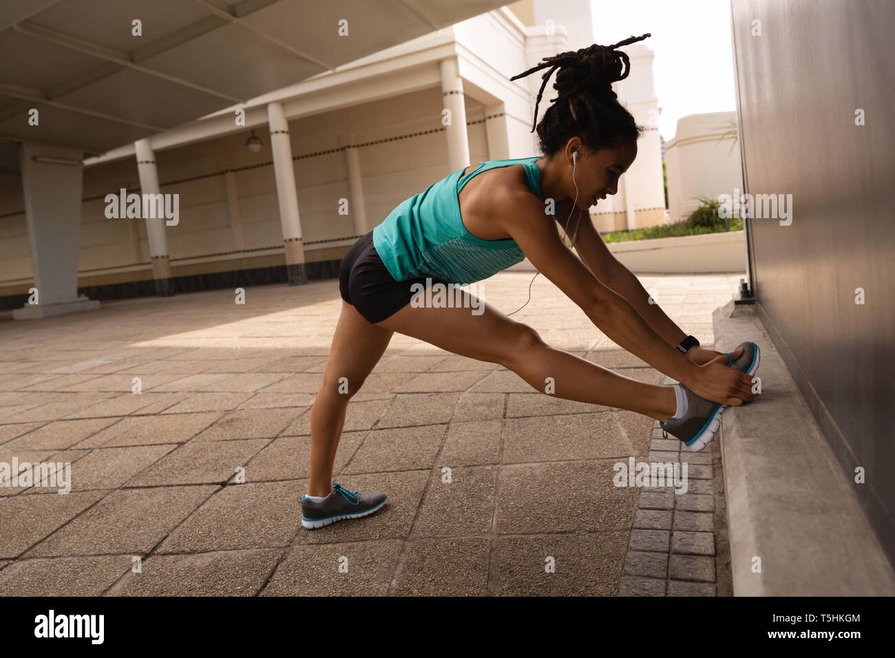 Donna ascoltando musica in cuffia mentre si esercita nella città Foto Stock