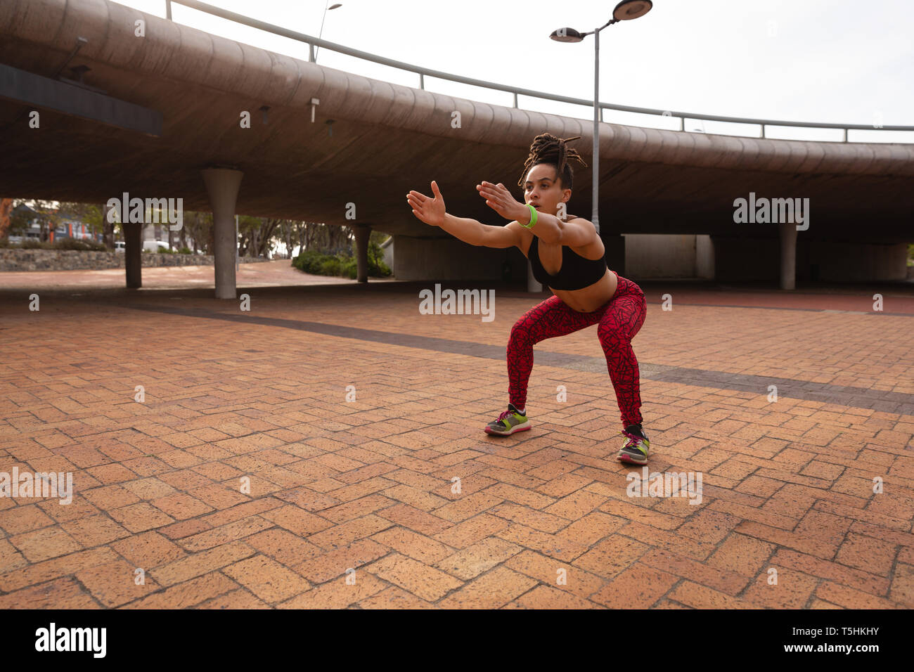 Donna facendo esercizio squat nella città 4k Foto Stock