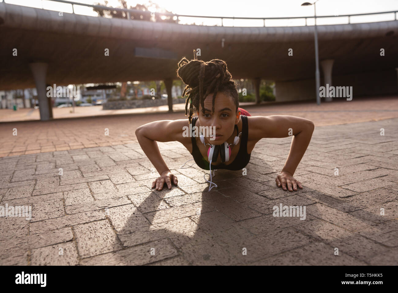 Giovane donna facendo push-up esercizio nella città Foto Stock