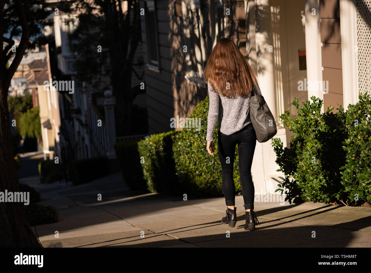 Donna che cammina sulla strada in una giornata di sole Foto Stock