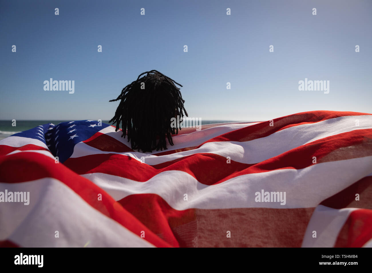 Uomo con bandiera americana presso la spiaggia in una giornata di sole Foto Stock