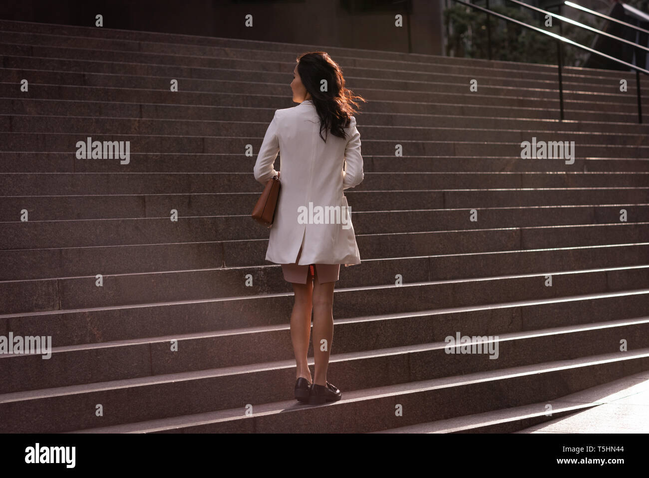 Premurosa donna in piedi a scale in una giornata di sole Foto Stock