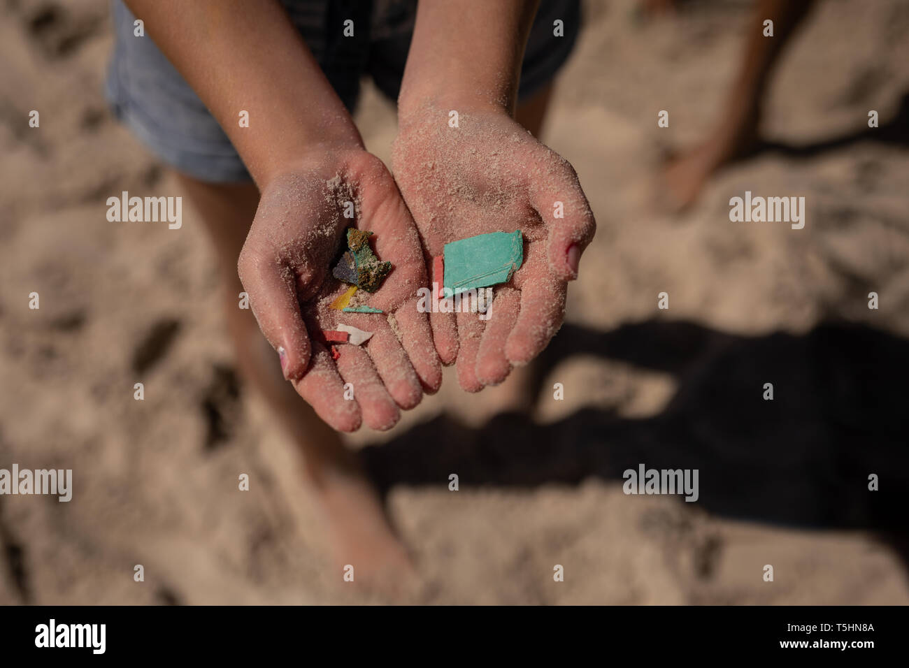 Volunteer che detengono rifiuti in mano alla spiaggia in una giornata di sole Foto Stock