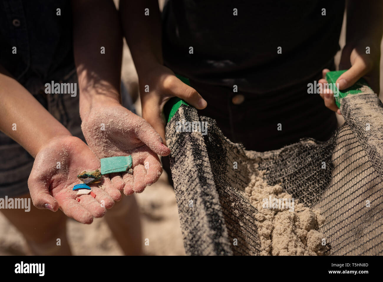 I volontari che detengono rifiuti in mano alla spiaggia in una giornata di sole Foto Stock