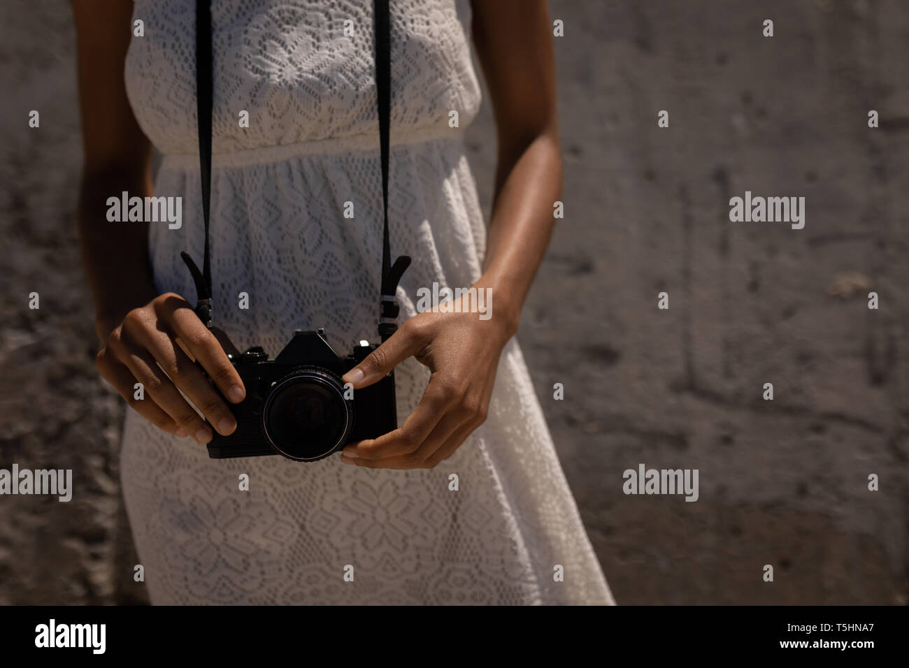 Donna in piedi con la fotocamera in spiaggia in una giornata di sole Foto Stock