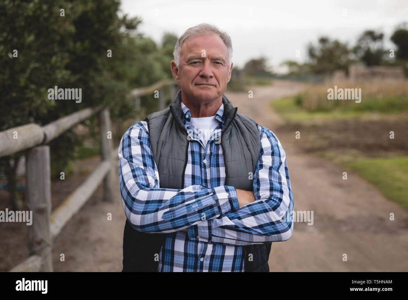 Senior maschili agricoltore in piedi con le braccia incrociate Foto Stock