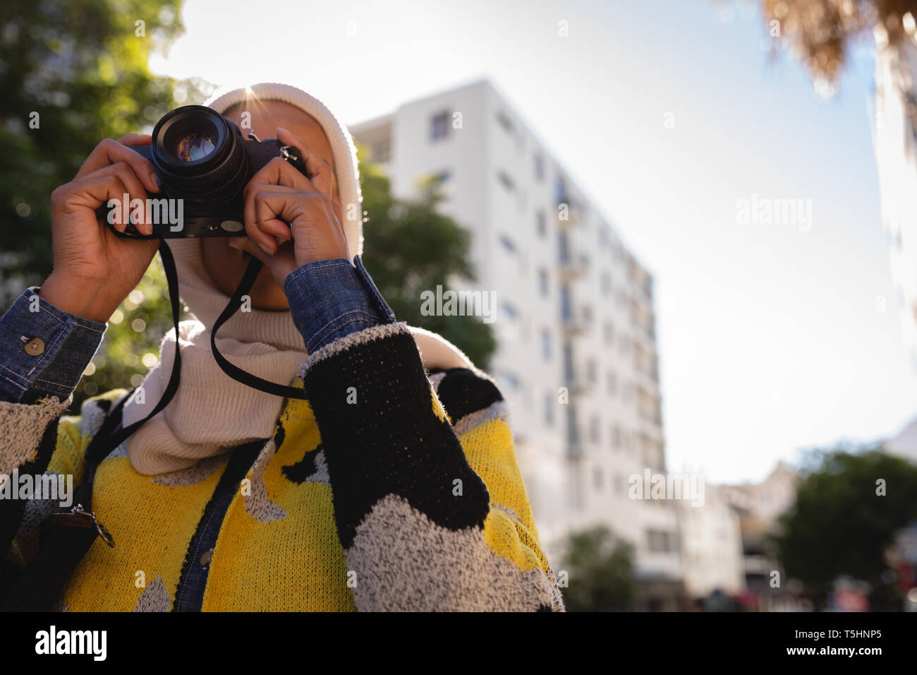 Donna che utilizza una fotocamera digitale in strada strada in una giornata di sole Foto Stock