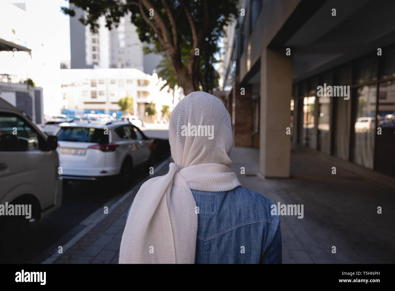 Donna con hijab a piedi la strada in una giornata di sole Foto Stock