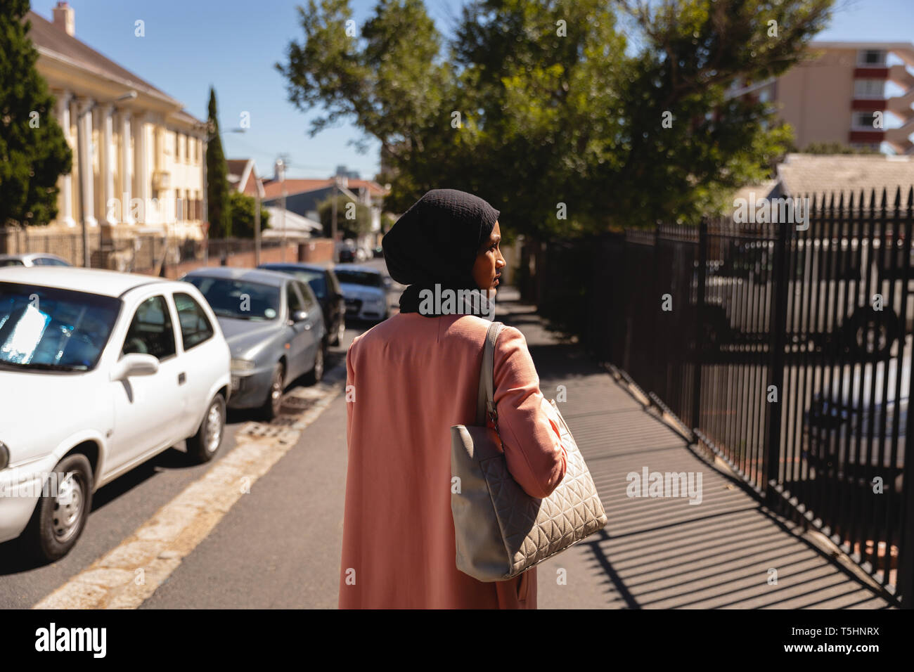 Premurosa donna in piedi in strada in una giornata di sole Foto Stock
