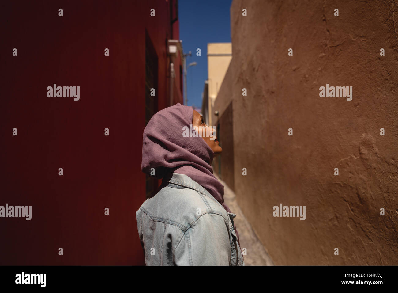Premurosa donna che guarda verso l'alto mentre in piedi in vicolo Foto Stock