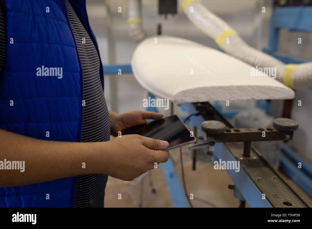 Uomo con tavoletta digitale in officina Foto Stock
