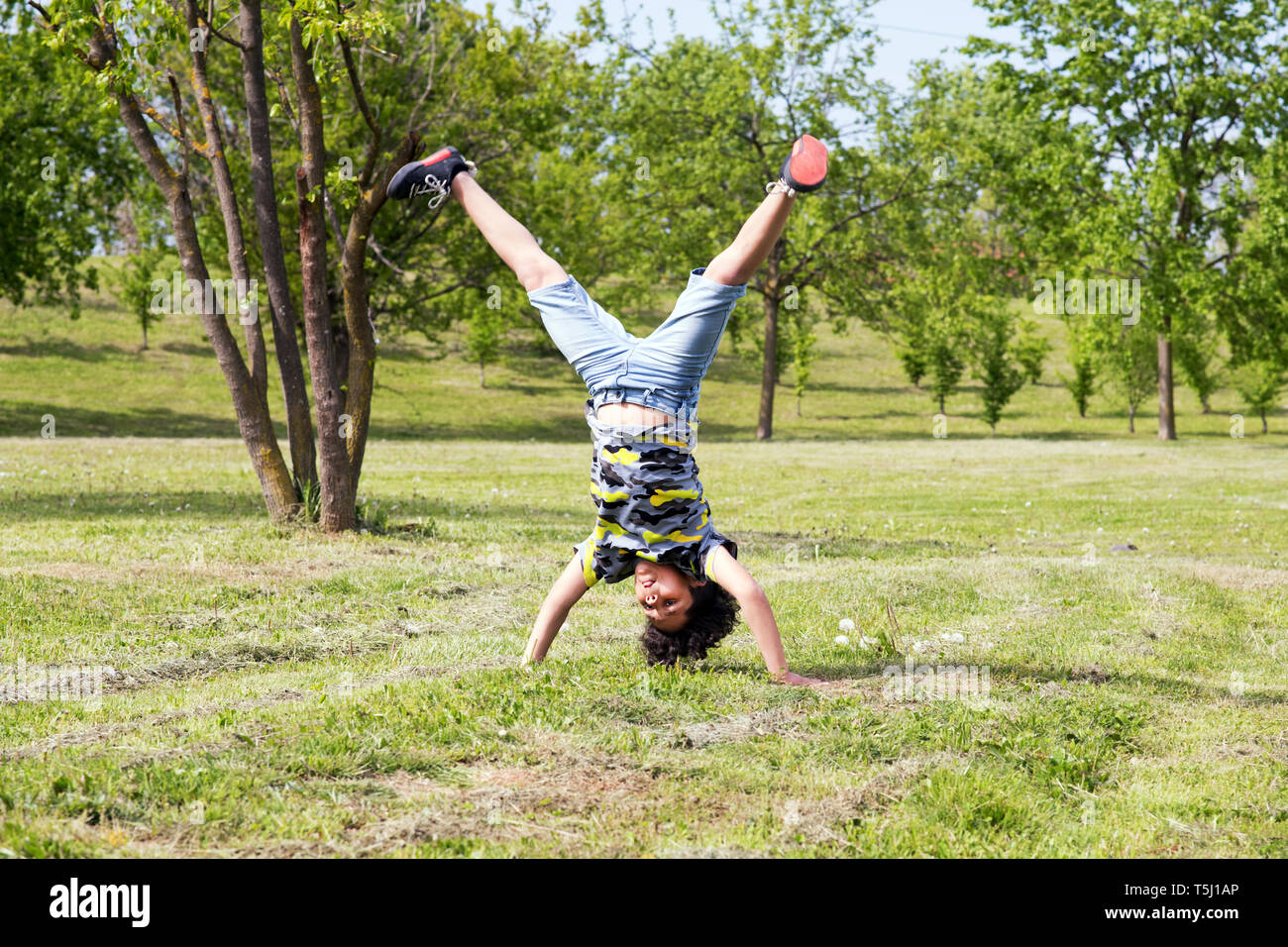 Atletica Giovane ragazzo in pratica mano sorge nel parco il bilanciamento con la sua gambe divaricate tra alberi di primavera Foto Stock
