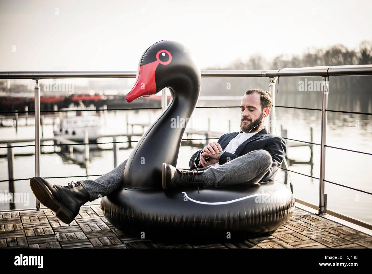 Hip imprenditore lavora su una casa galleggiante, un salotto galleggiante, swan utilizzando smartwatch Foto Stock