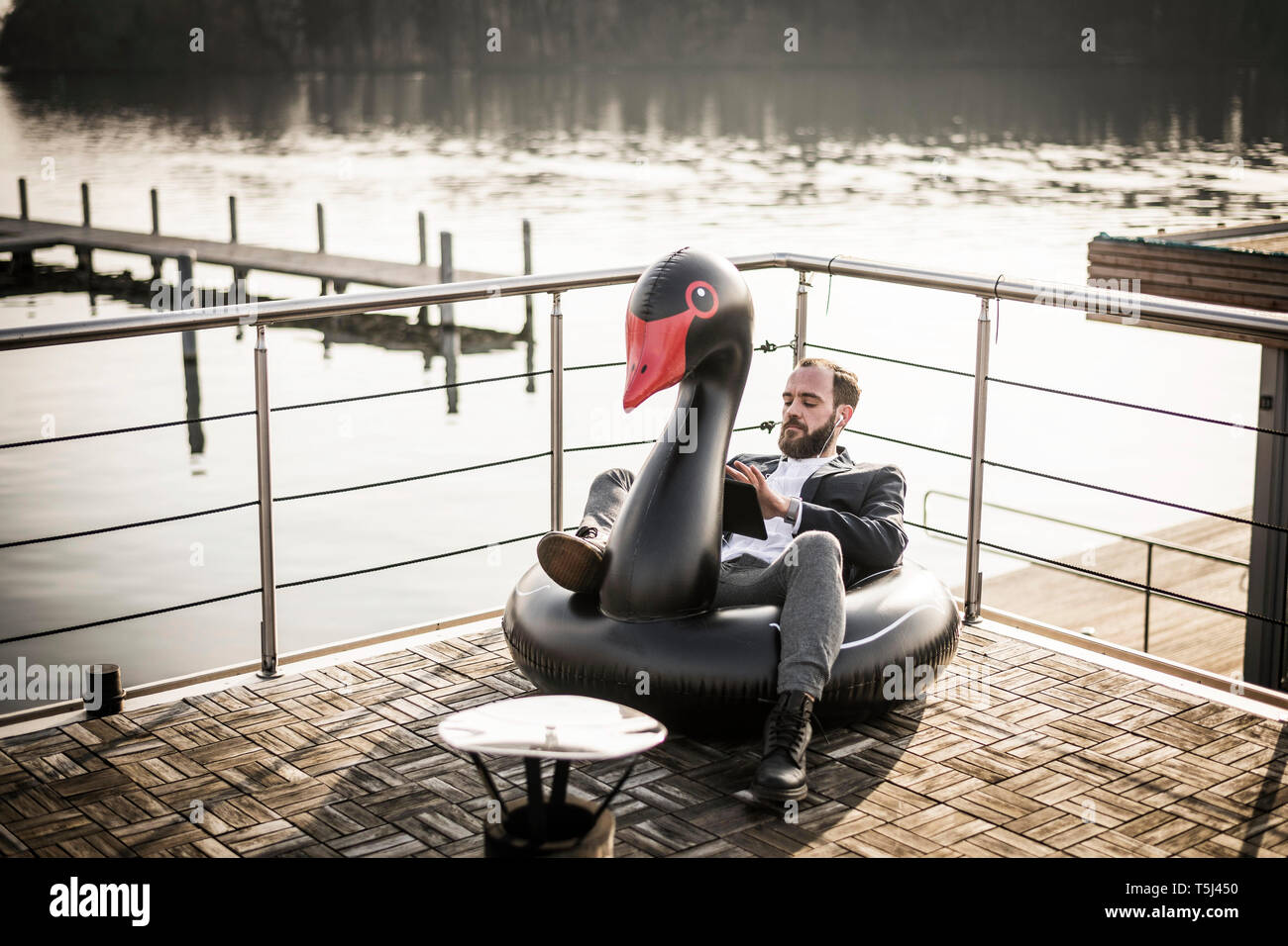 Hip imprenditore lavora su una casa galleggiante, un salotto galleggiante, swan con tavoletta digitale Foto Stock