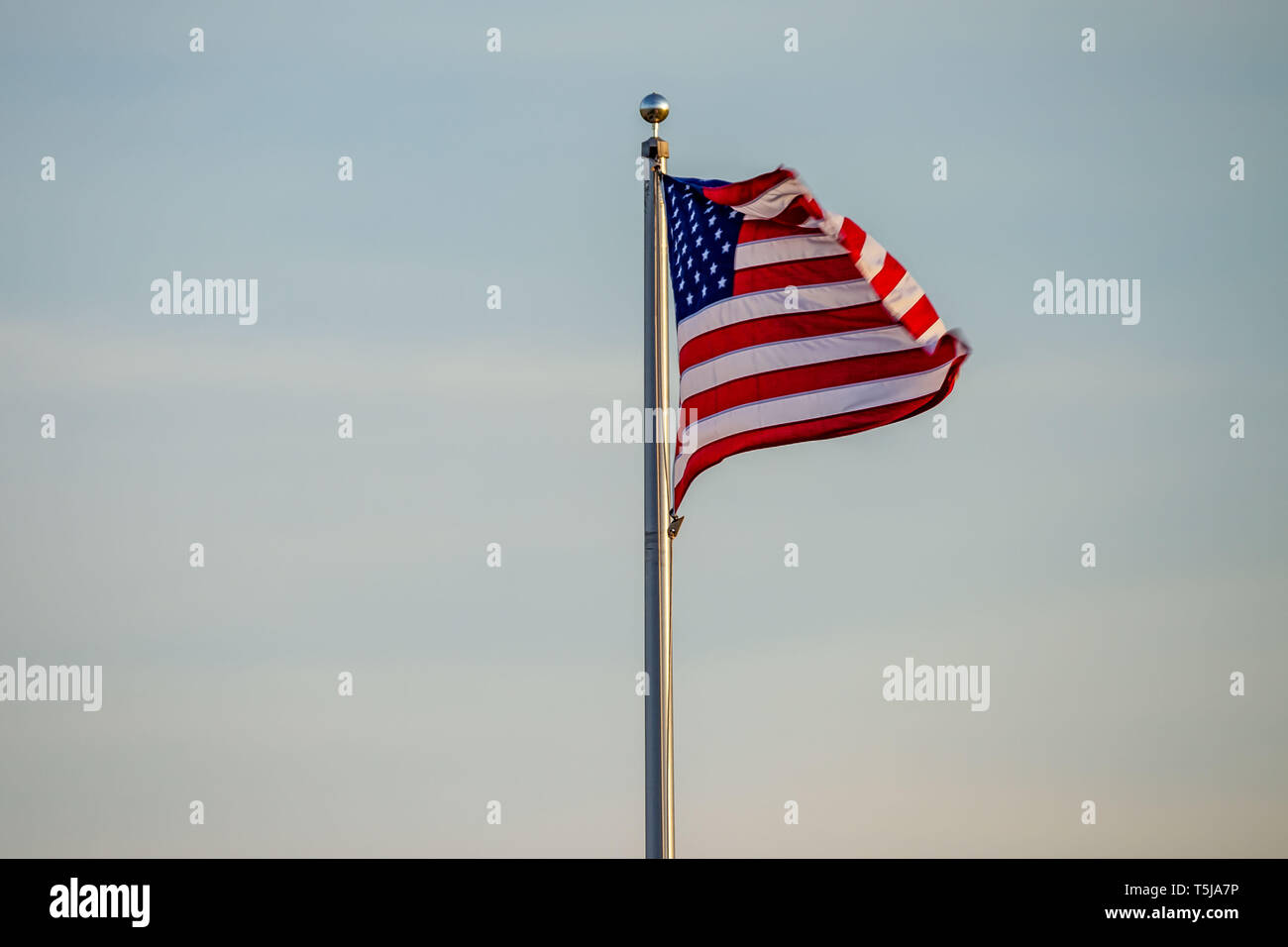 La bandiera americana turbinano nella brezza all'alba Foto Stock