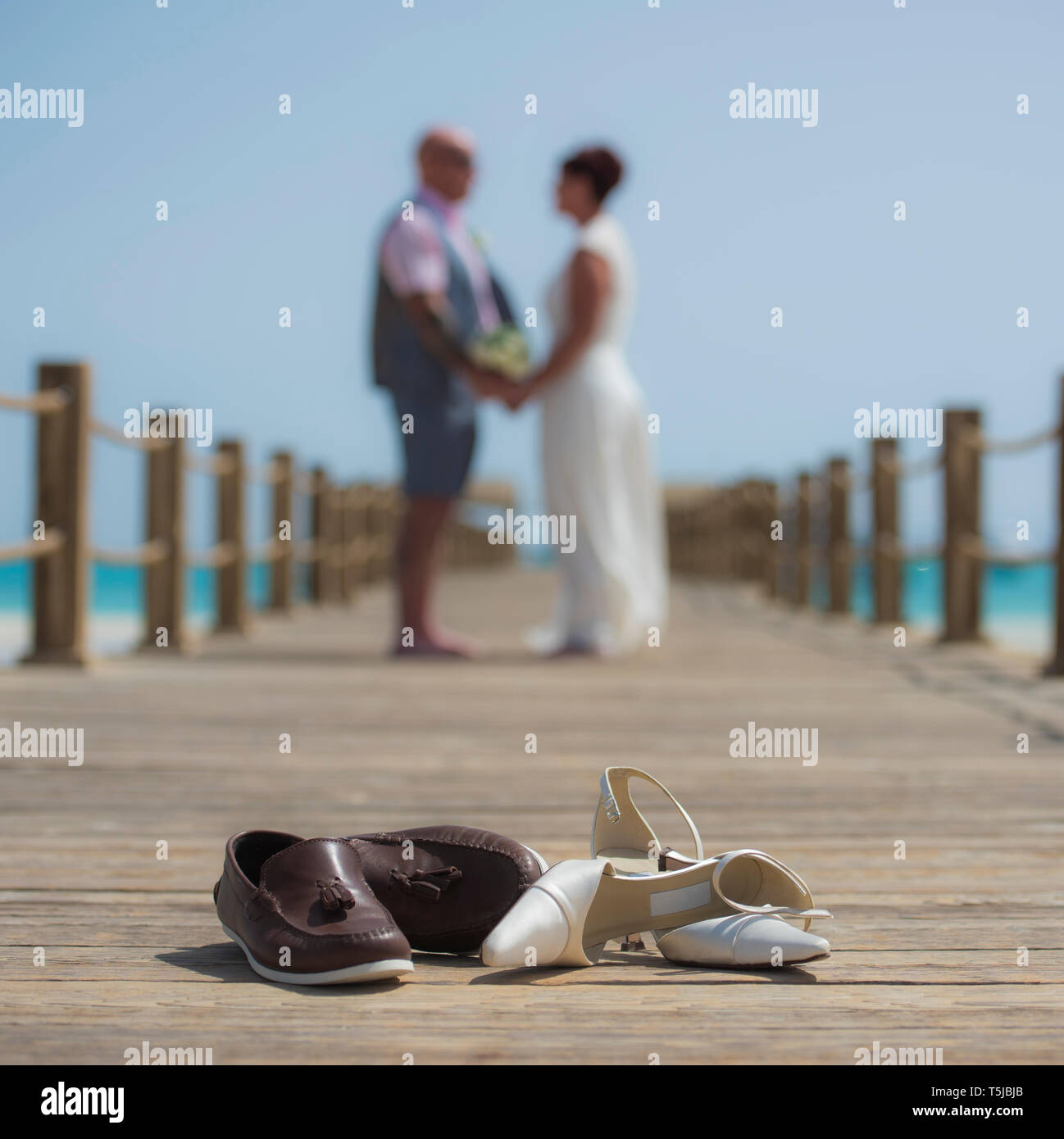 Coppia sposata sul giorno di nozze camminando romanticamente esterno sul molo in legno con un paio di scarpe in primo piano Foto Stock