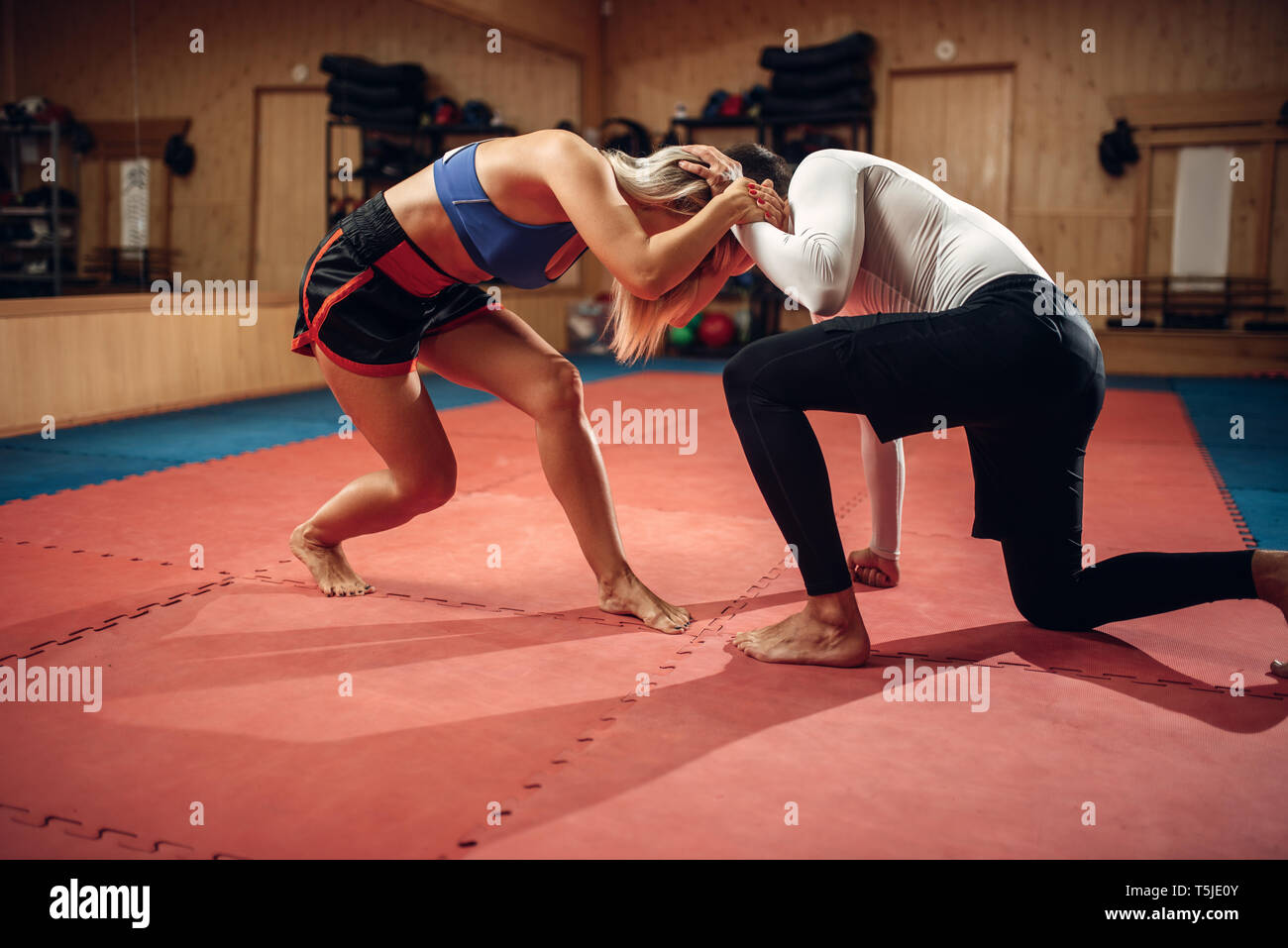 Persona femmina trattiene il grip, auto-difesa allenamento con connettore maschio di tipo personal trainer, palestra interno su sfondo. Donna su auto-difesa della formazione Foto Stock