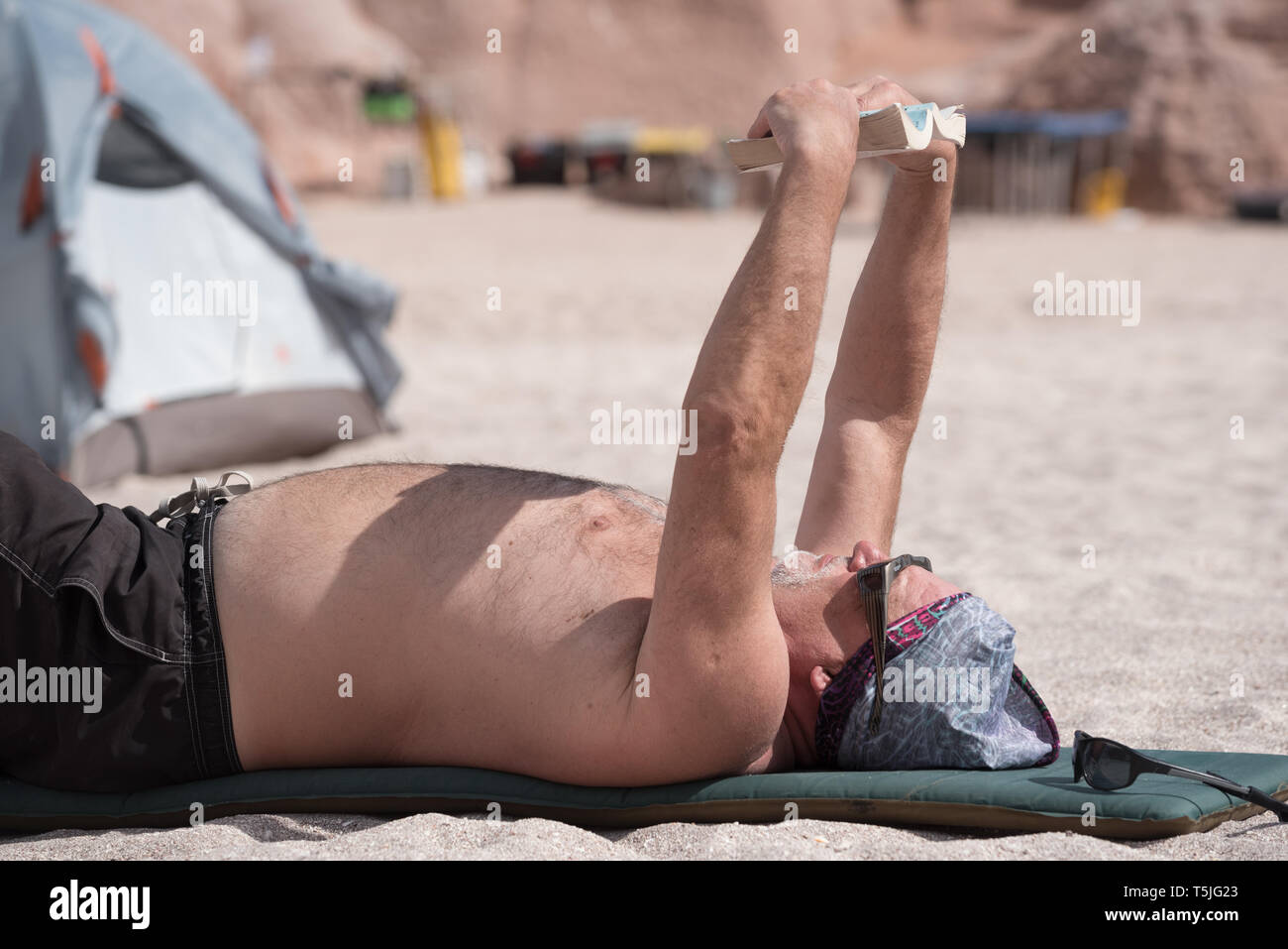 La lettura di un libro su un kayak di mare viaggio, Espiritu Santo Isola, BCS, Messico Foto Stock