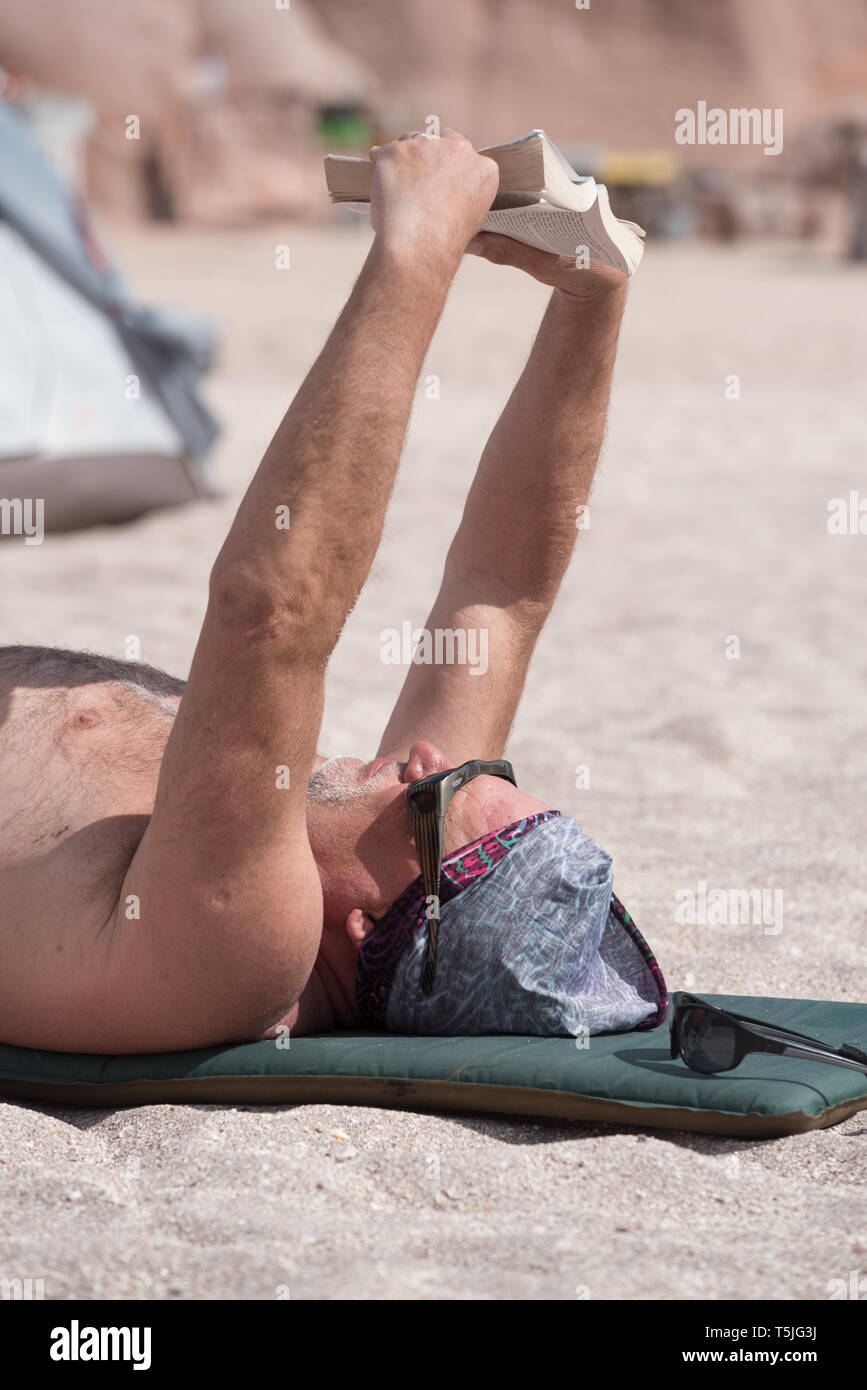 La lettura di un libro su un kayak di mare viaggio, Espiritu Santo Isola, BCS, Messico Foto Stock