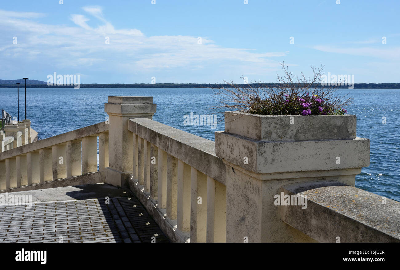 Vista prospettica di una vecchia strada con corrimano in pietra nella città di Orbetello, Toscana, Italia, su una soleggiata giornata di primavera. L omonima laguna in background Foto Stock