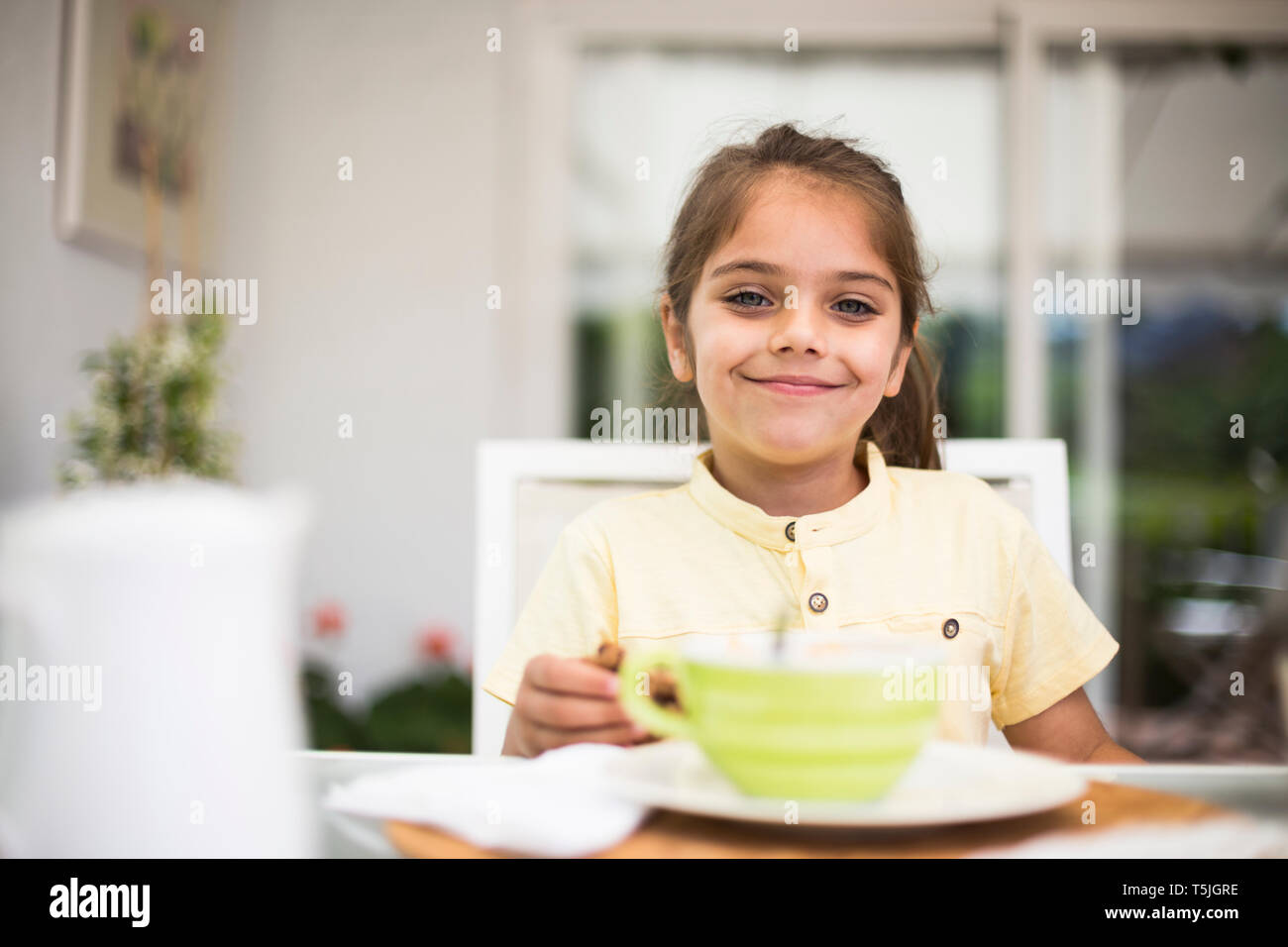 Ritratto di sorridente bambina avente la colazione a casa Foto Stock