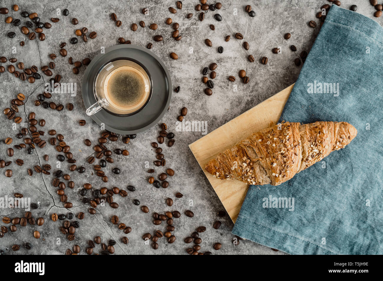 Bicchiere di caffè nero e un intero pasto croissant con grani Foto Stock