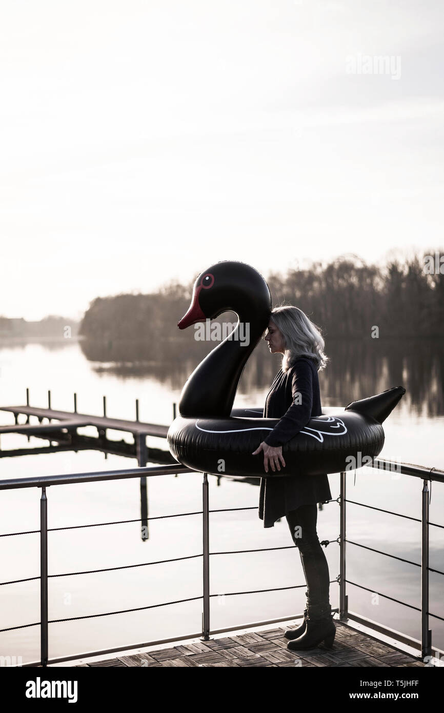Imprenditrice con swan flottante in piedi su una casa galleggiante Foto Stock