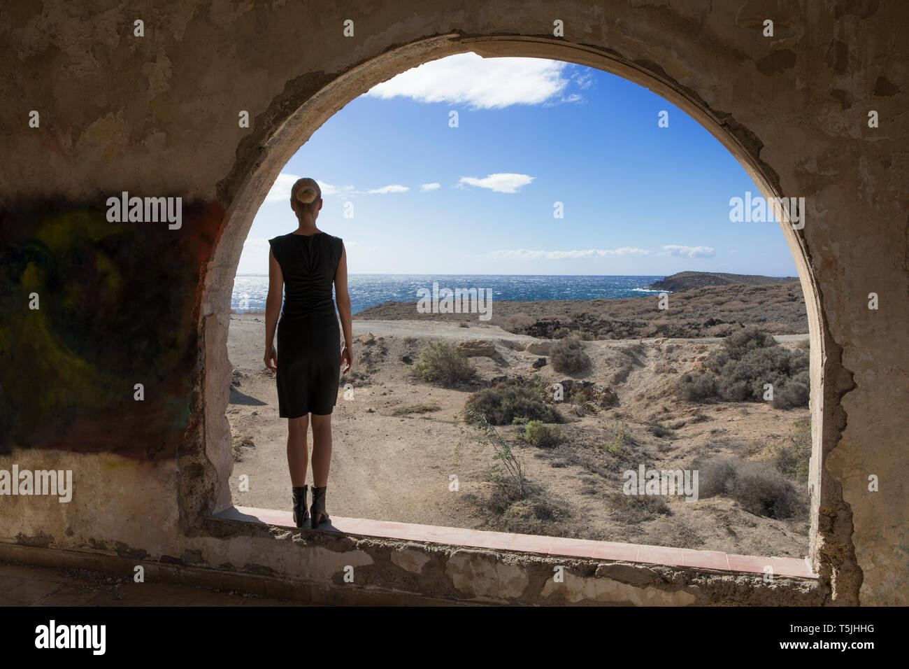 Spagna, Tenerife, Abades, Sanatorio de Abona, donna in piedi alla finestra ad arco in Ghost Town building Foto Stock