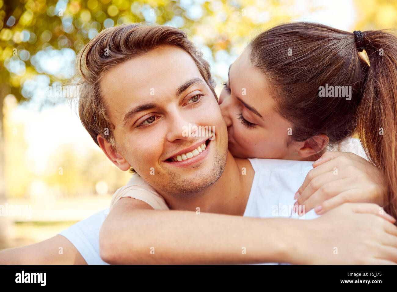 Felice coppia giovane in amore kissing presso un parco Foto Stock