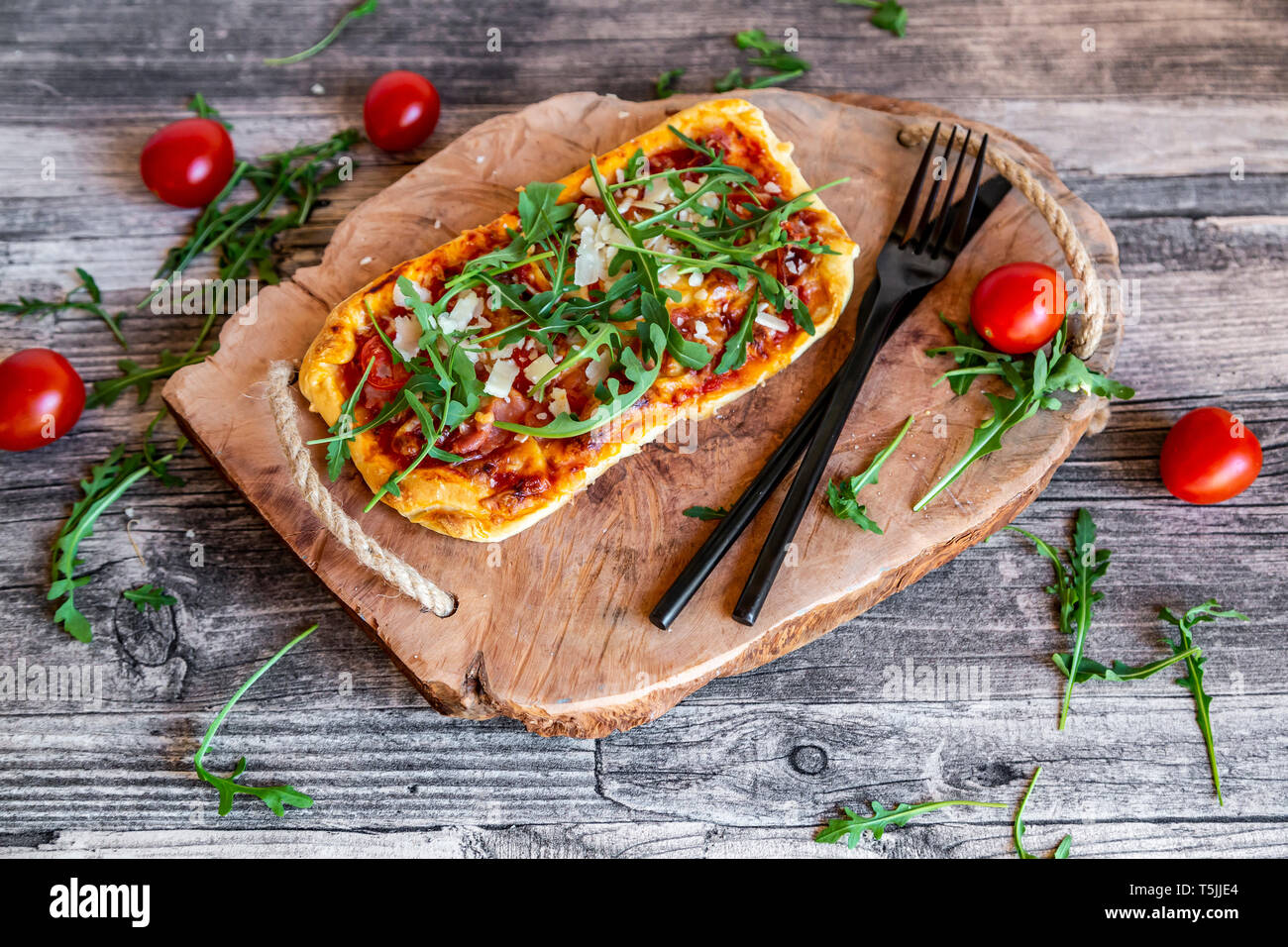In casa la pizza con rucola e prosciutto di Parma, pomodoro e scaglie di parmigiano Foto Stock
