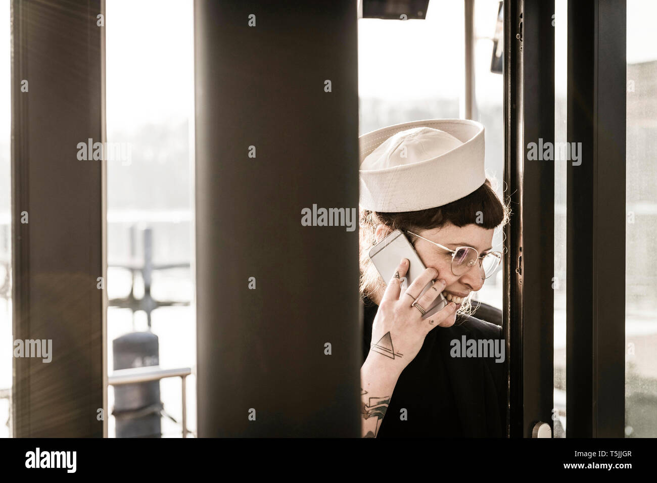 Una donna con il Sailor's hat utilizza lo smartphone in una casa galleggiante Foto Stock