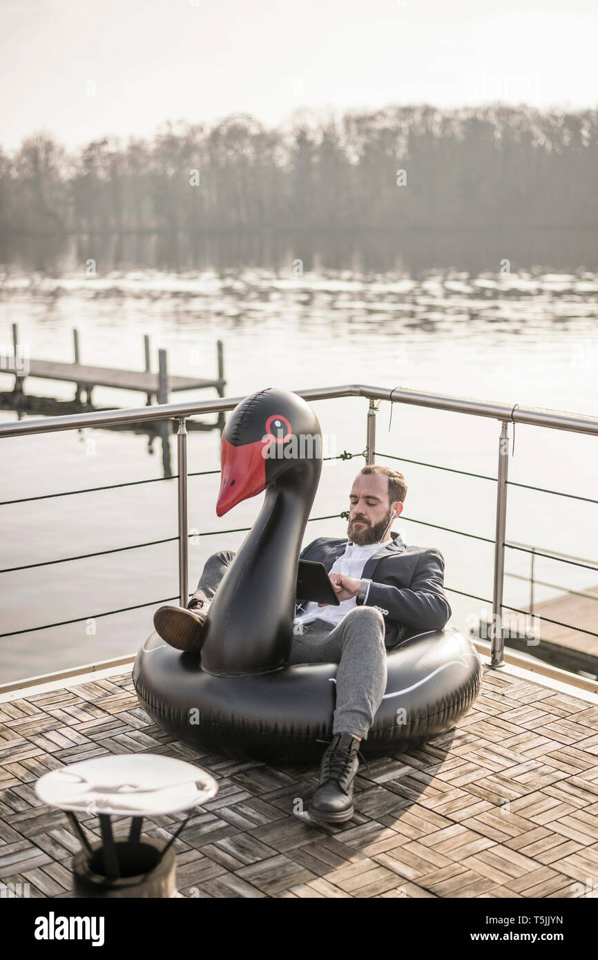 Hip imprenditore lavora su una casa galleggiante, un salotto galleggiante, swan con tavoletta digitale Foto Stock