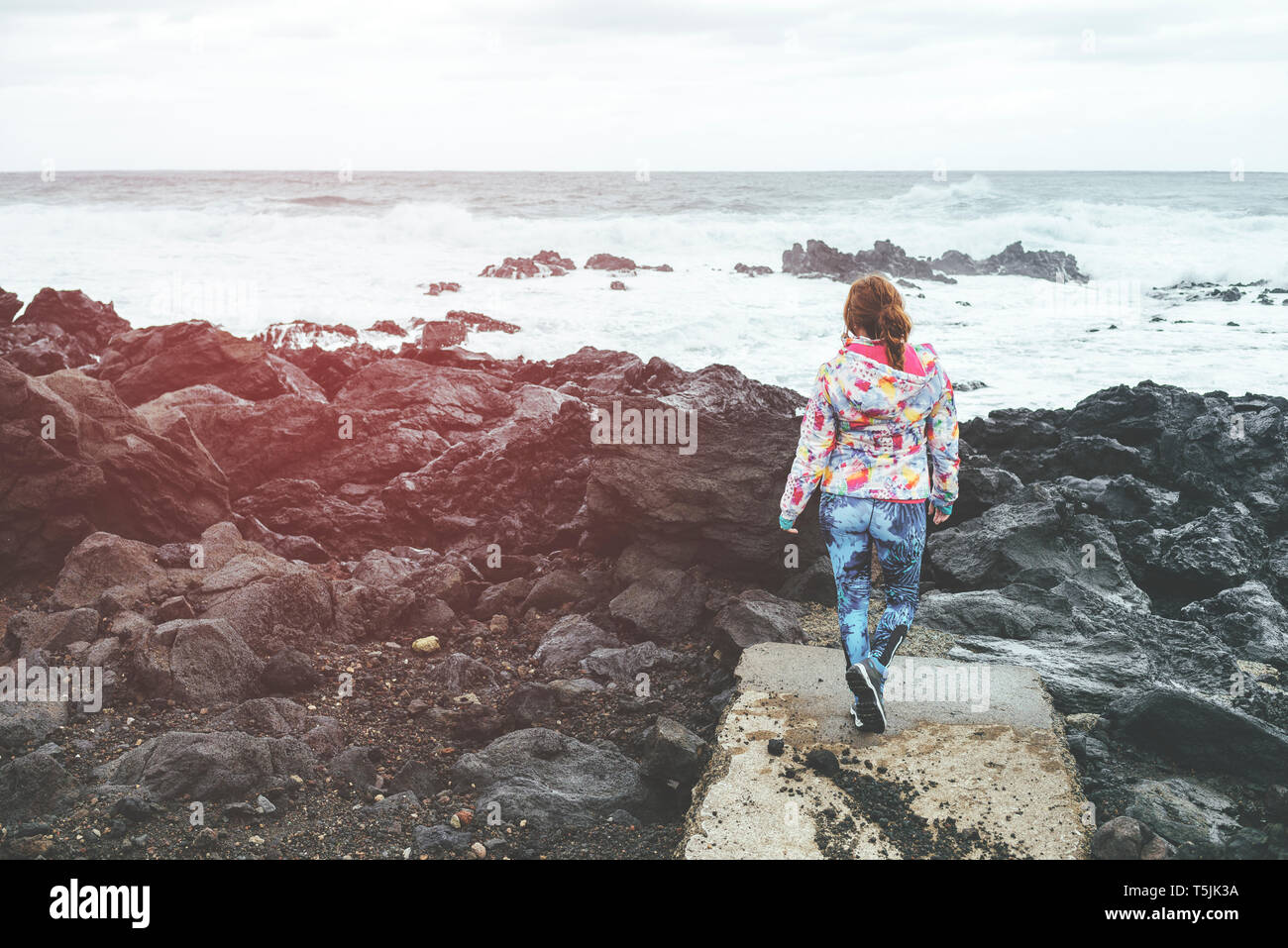 Il Portogallo, isole Azzorre, Sao Miguel, donna che guarda il mare dal paesaggio roccioso Foto Stock